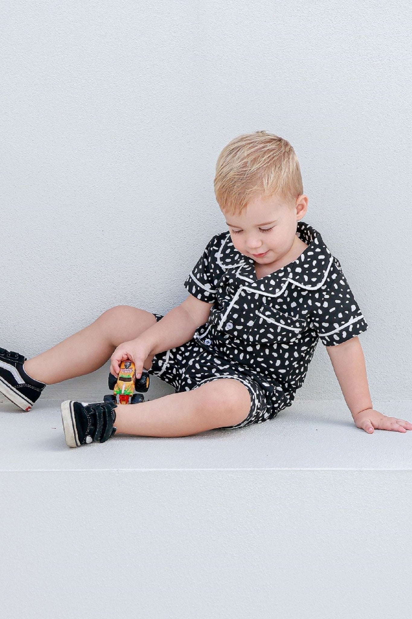 Boy sitting on the steps, playing with a toy truck while wearing cozy pajamas
