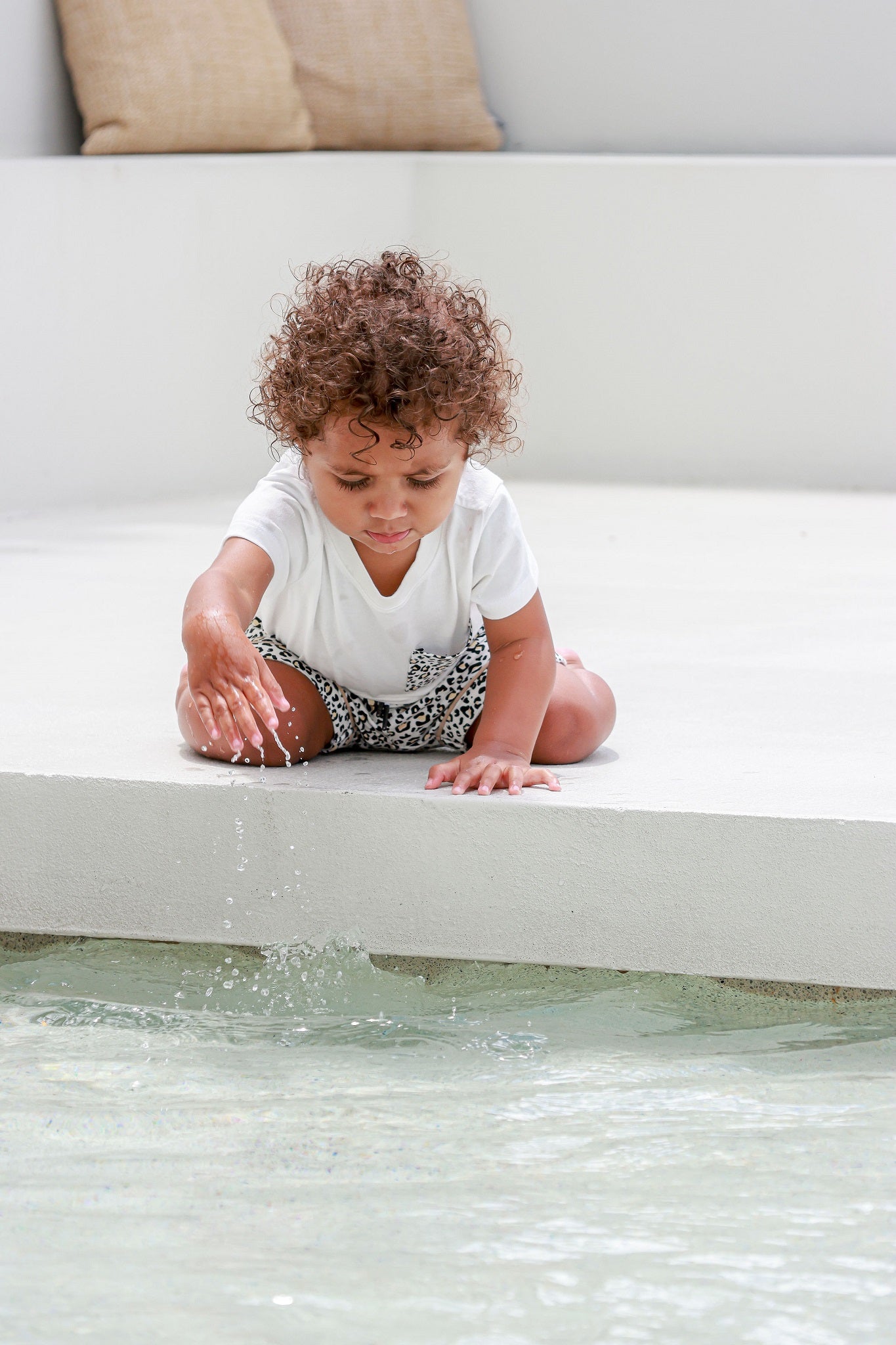 Kid sitting and wearing a leopard print pocket tee, enjoying a relaxed and stylish moment.