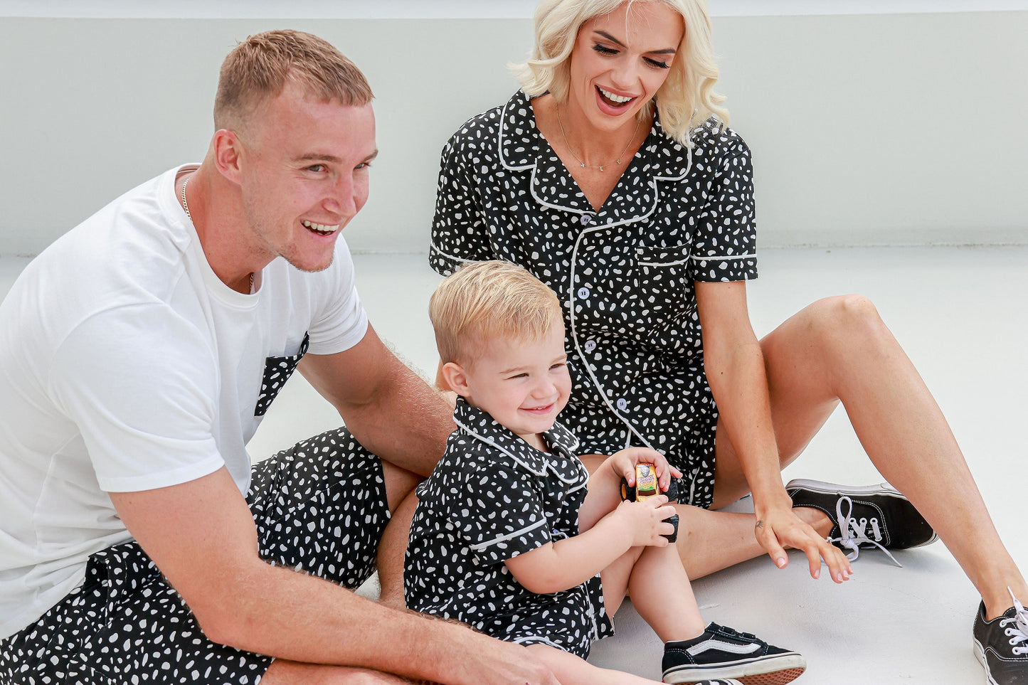 Mother, father, and son sitting together in matching pajamas, enjoying a warm and joyful family moment