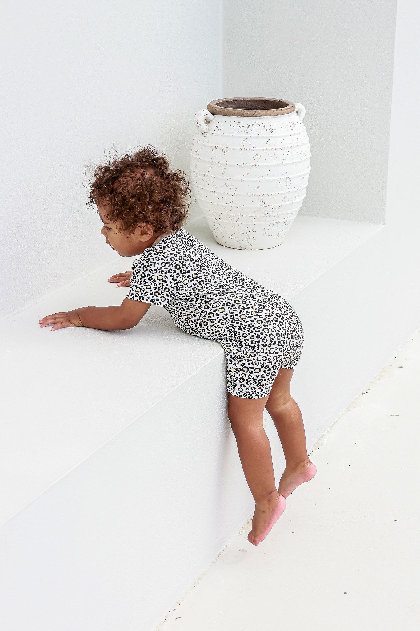 toddler boy climbing down a step wearing leopard print romper pyjamas