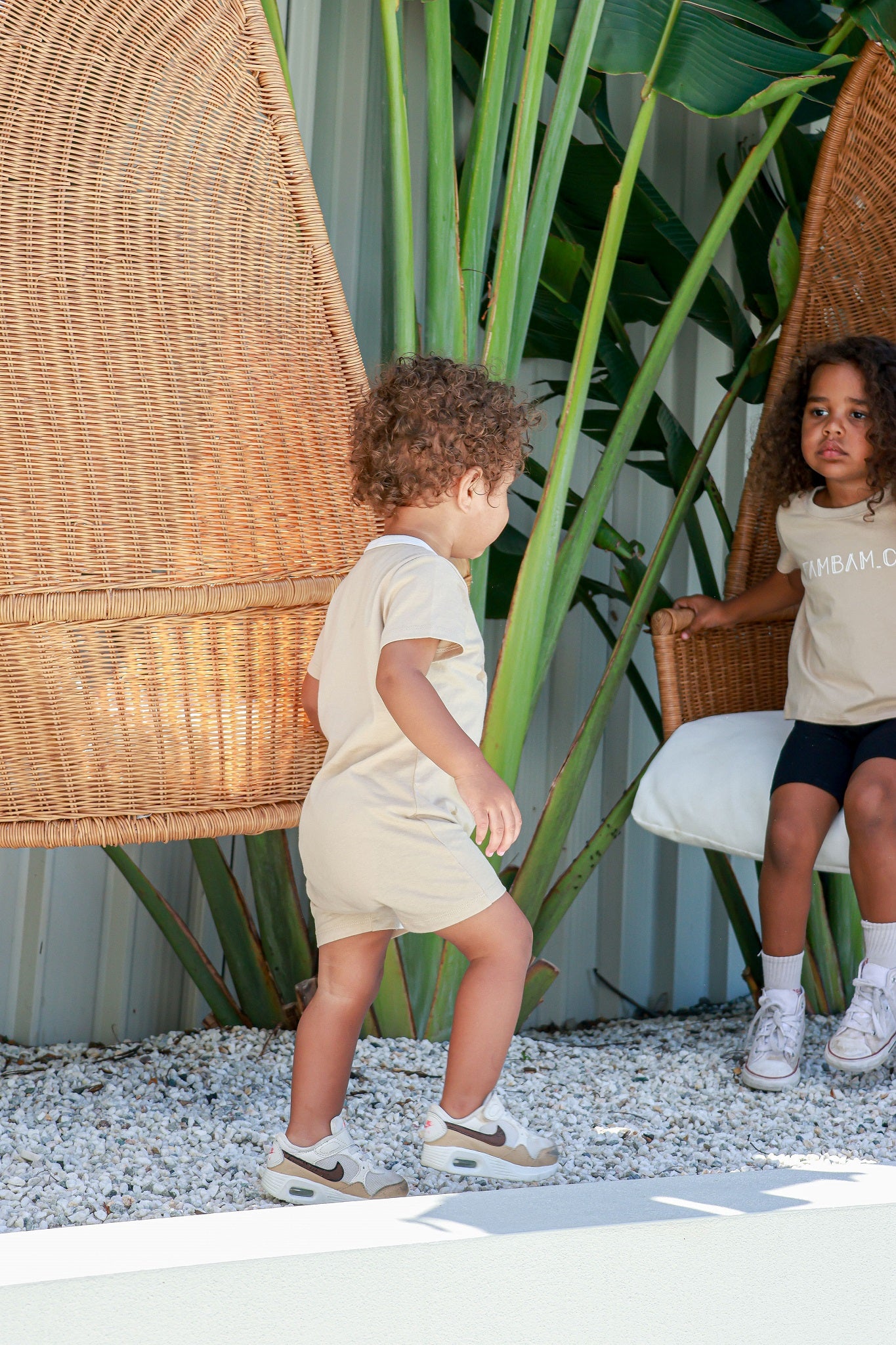Toddler boy wearing logo beige romper standing