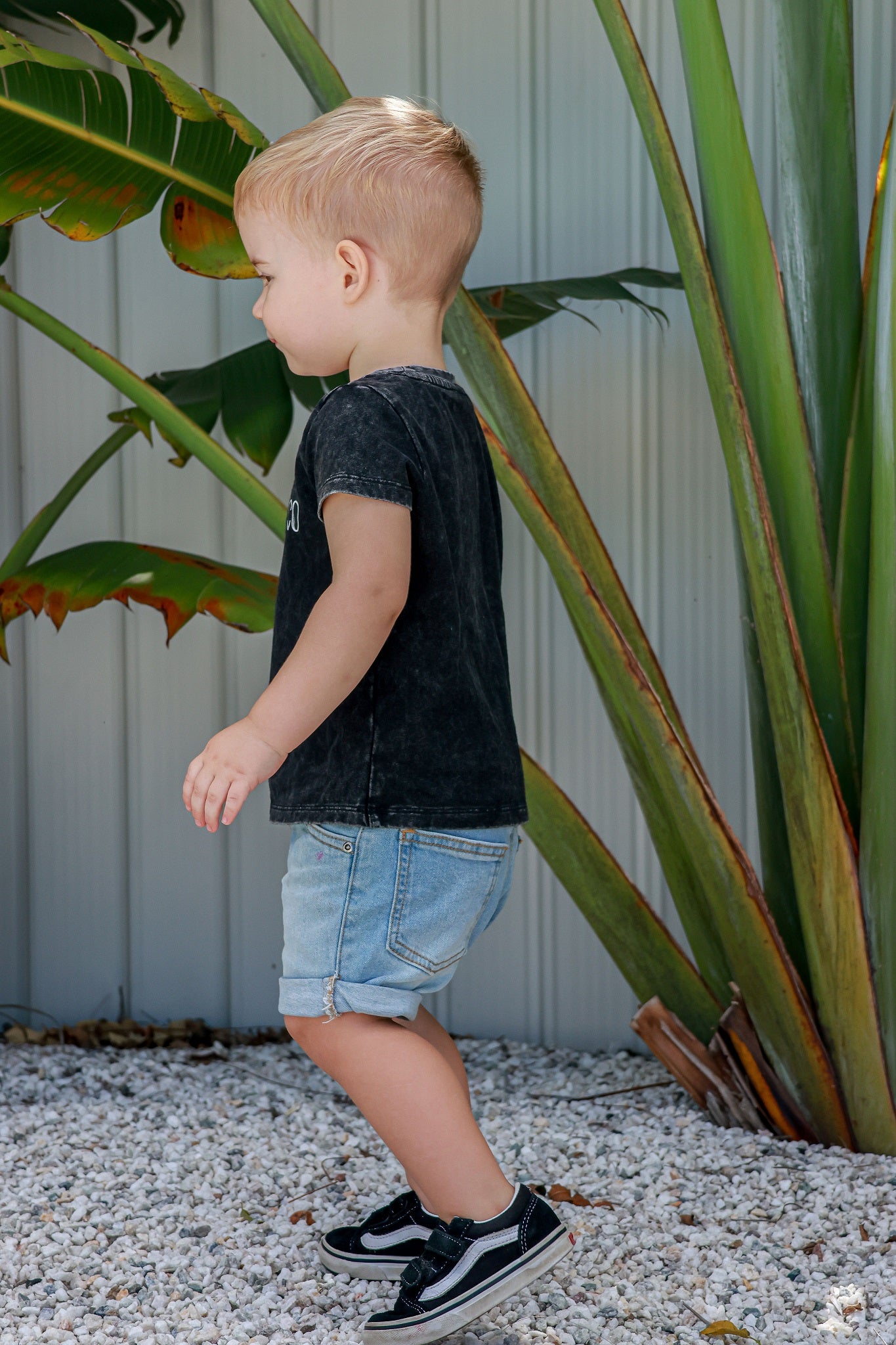 Toddler boy in logo acid wash shirt walking around on rocks