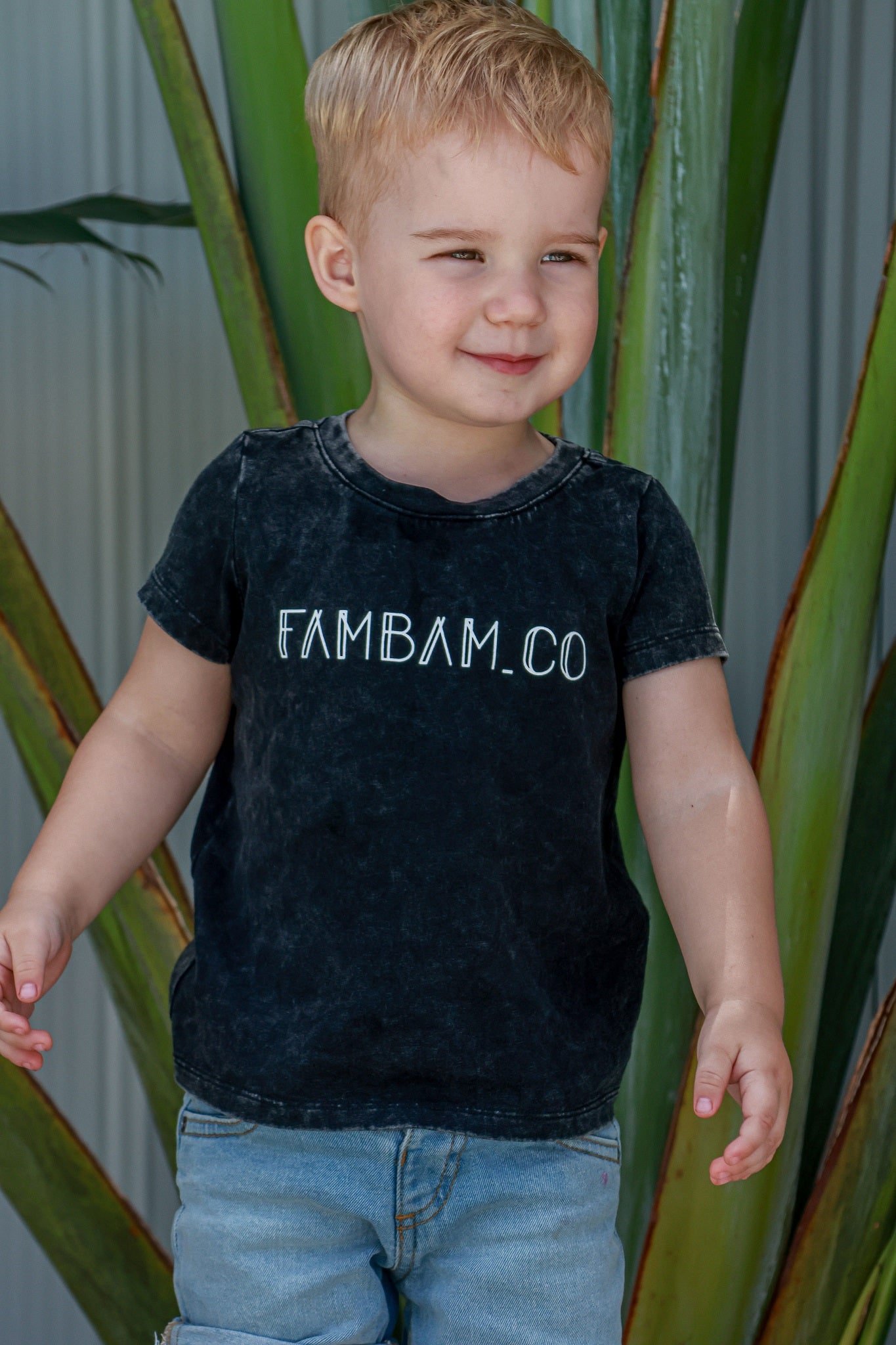 Toddler boy in logo acid wash shirt standing
