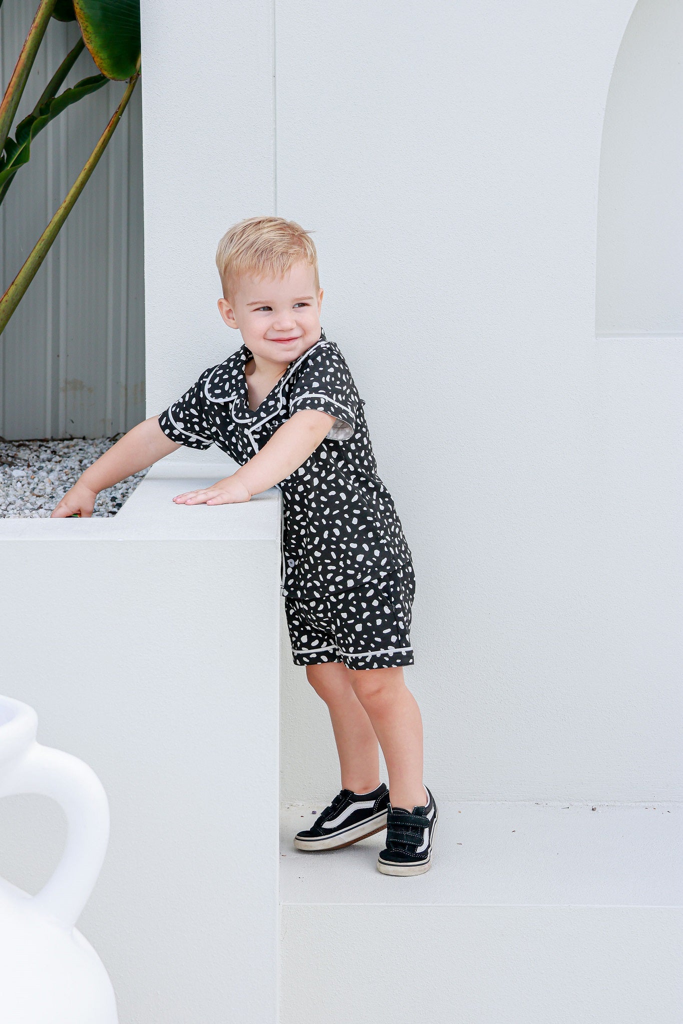 boy standing wearing pj shirt and shorts white and black pokadots