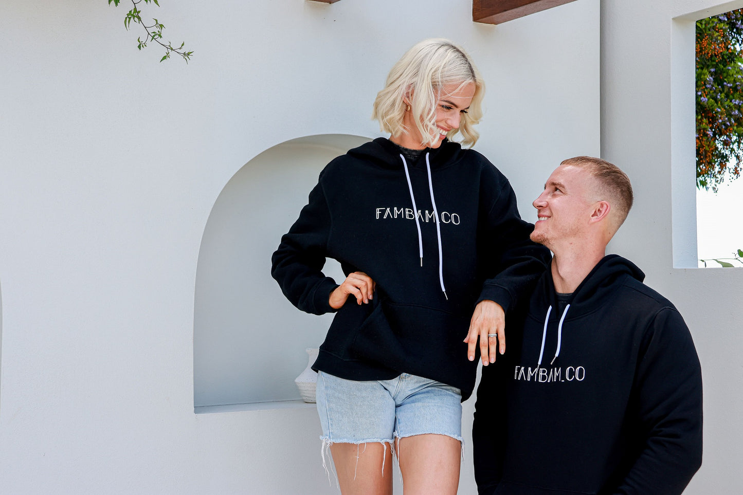 Couple standing together, looking into each other's eyes, both wearing matching hoodies, sharing a loving and stylish moment.