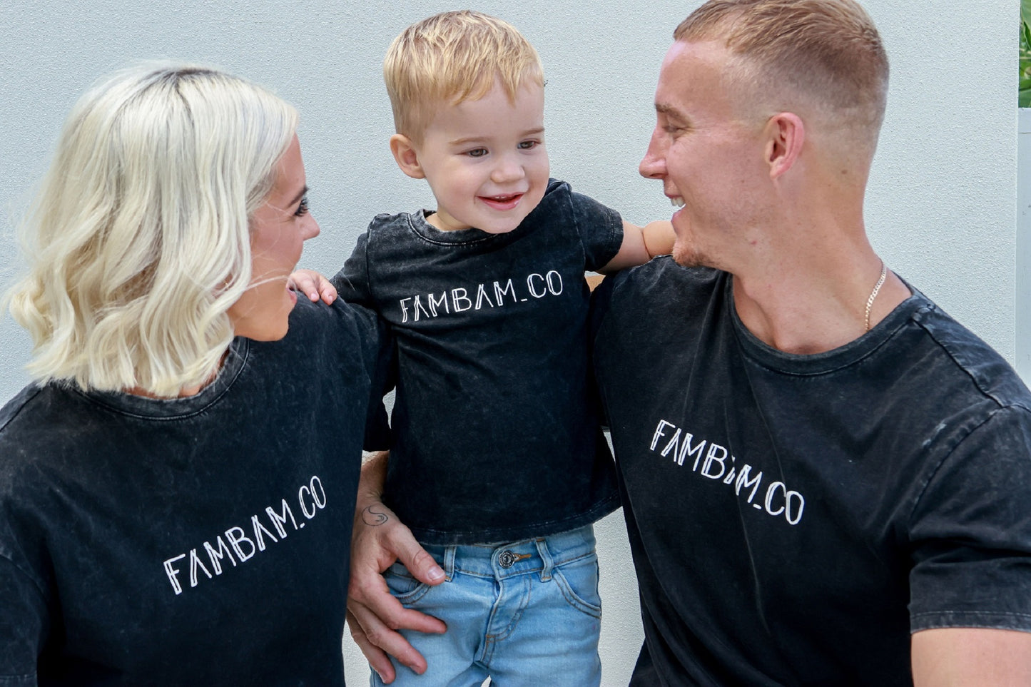 Family laughing and smiling while wearing matching acid wash shirts