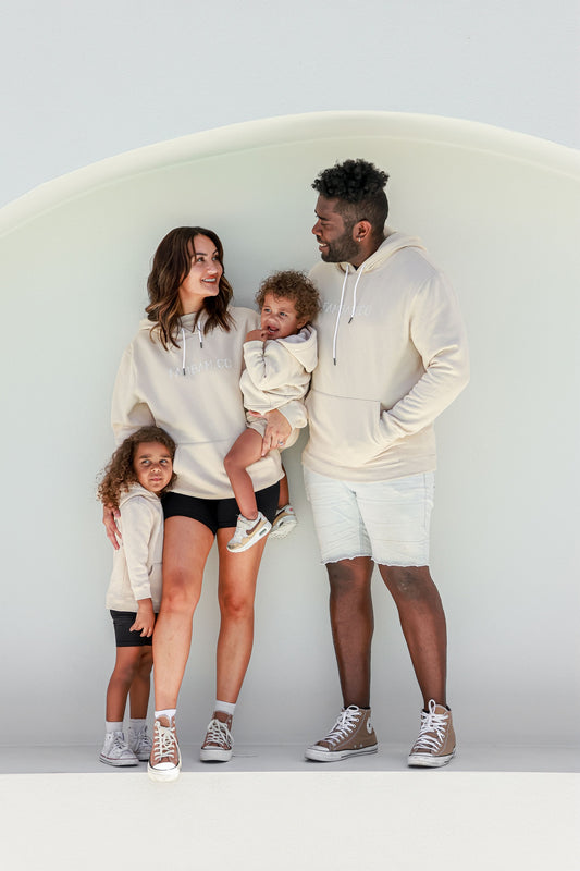 family standing together matching in beige hoodie jumpers smiling