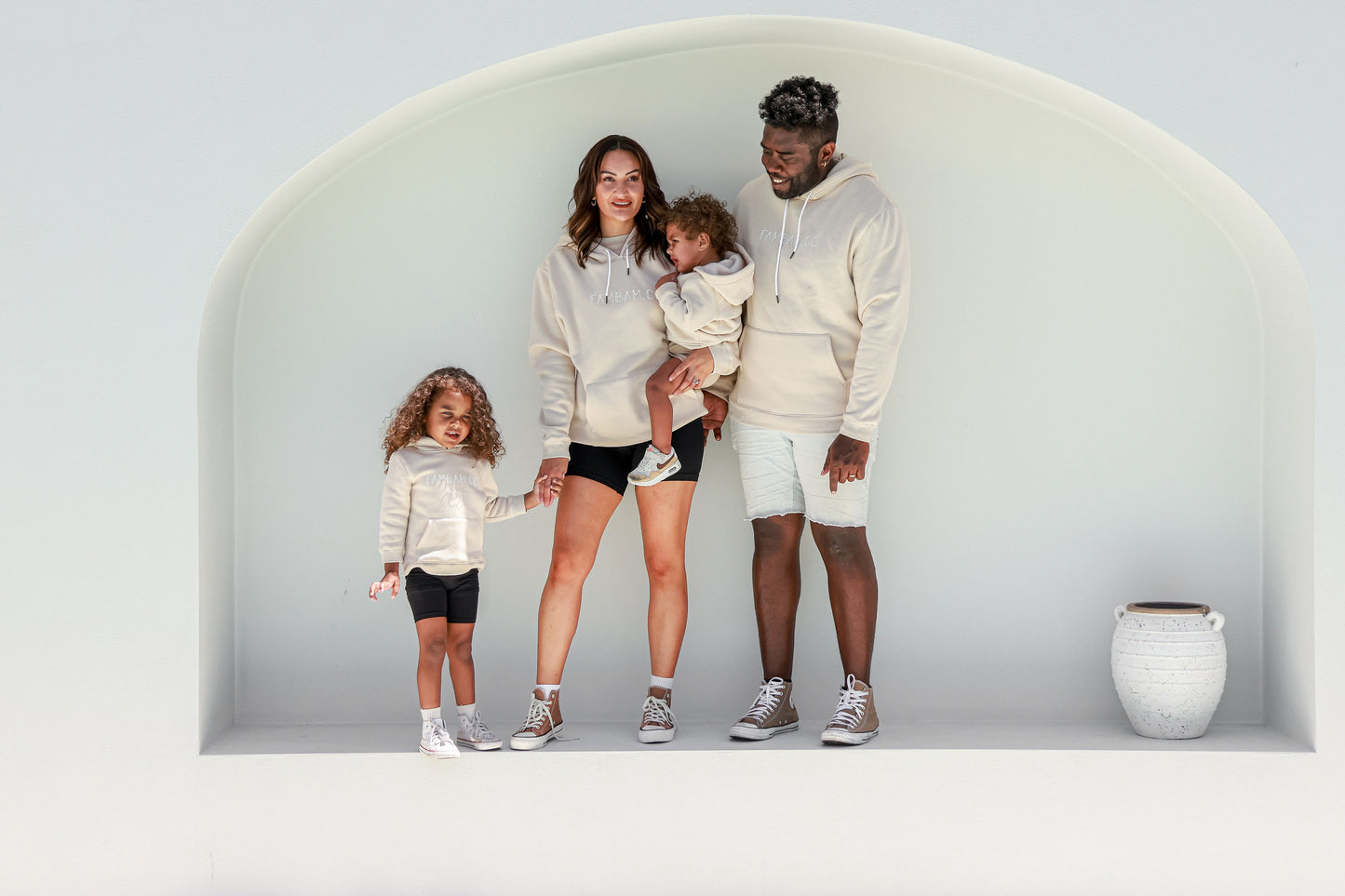 family standing together wearing matching beige hoodies jumpers