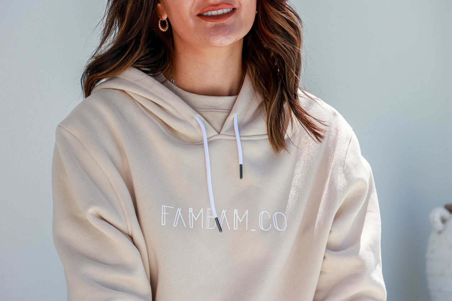 close up of a logo hoodie jumper in beige of a lady smiling
