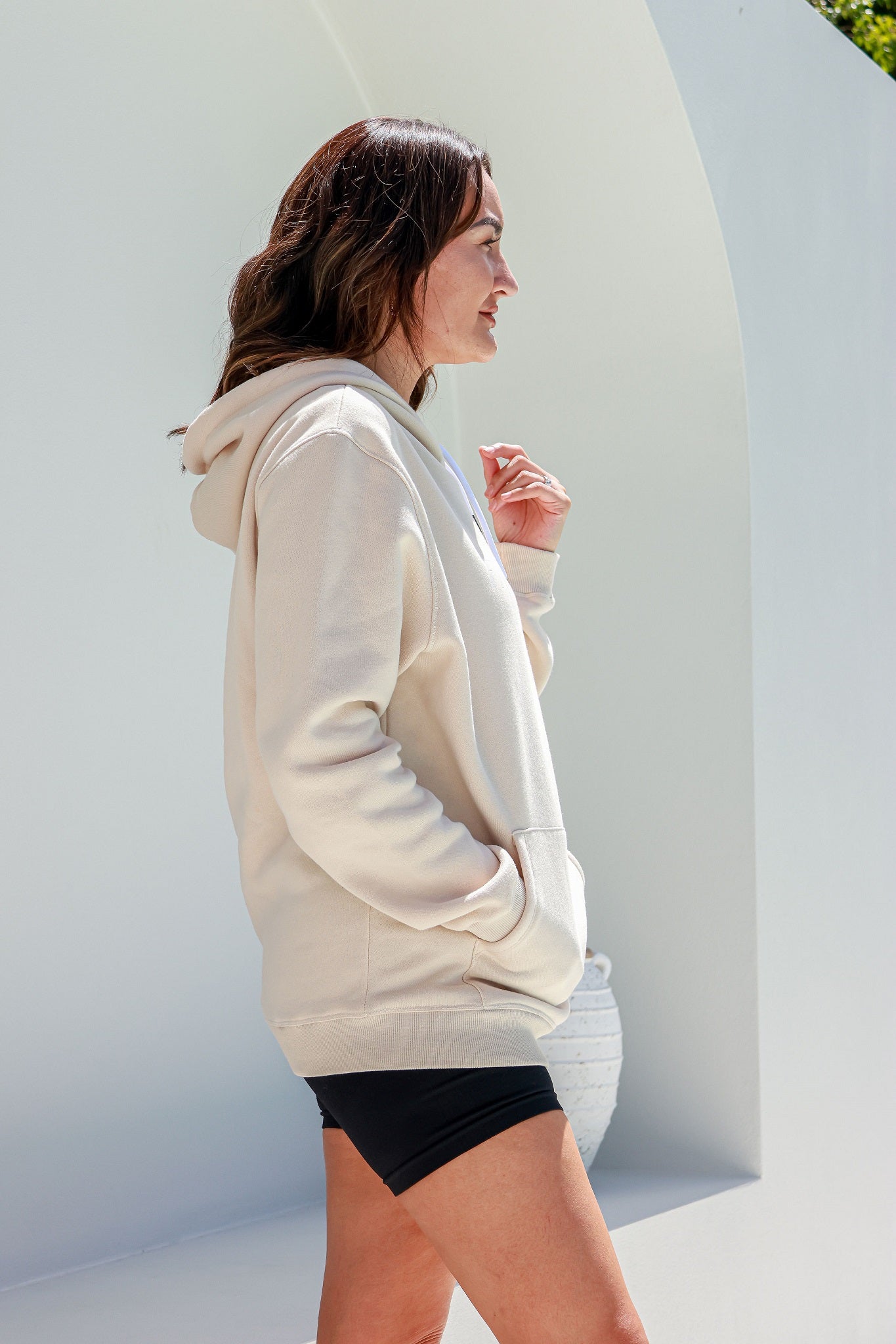 woman standing in a logo beige hoodie jumper