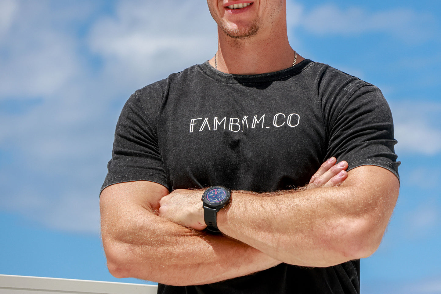 Close up of logo acid wash shirt on a guy with his arms crossed smiling