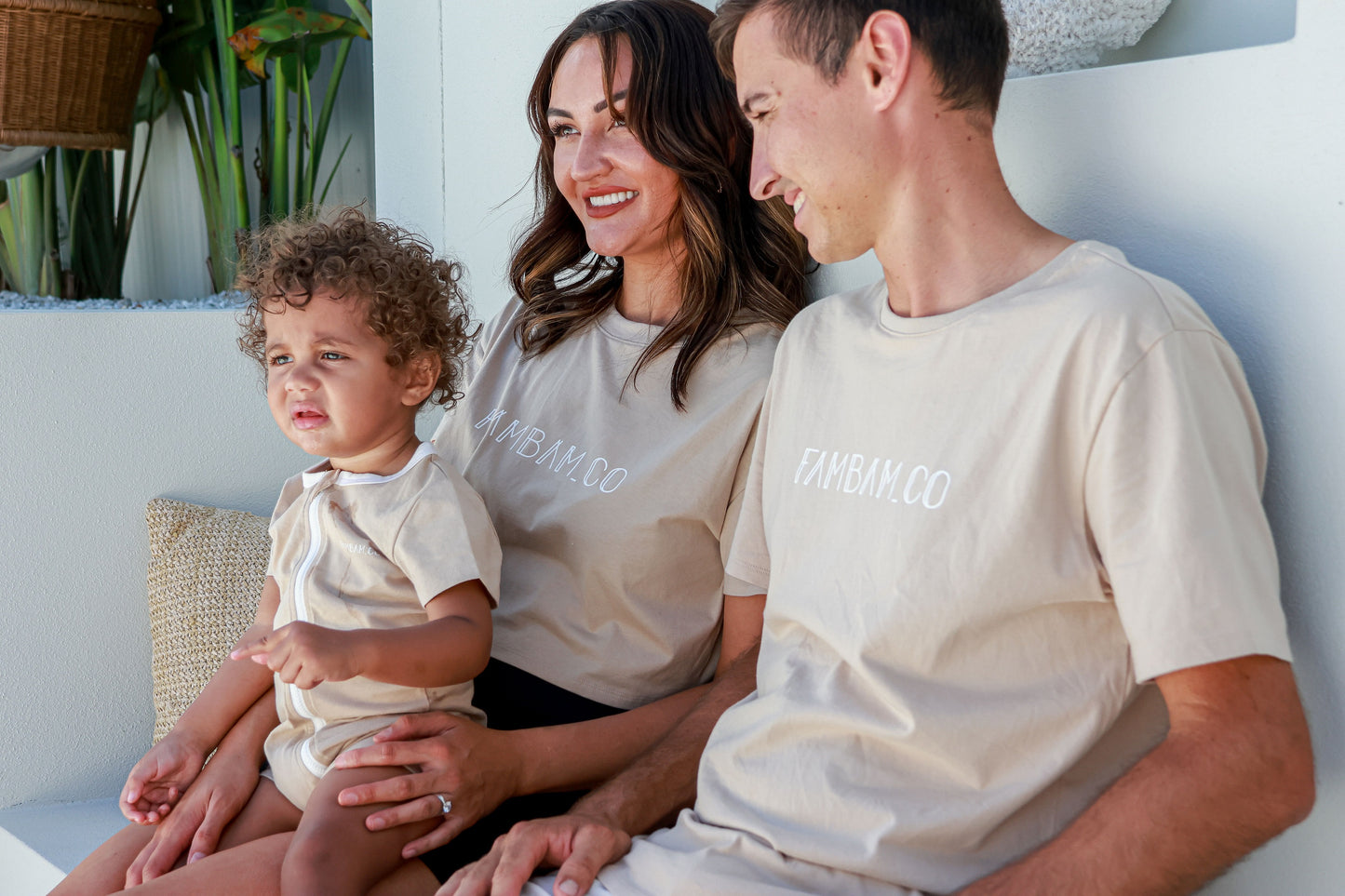 family wearing matching shirts sitting down together smiling