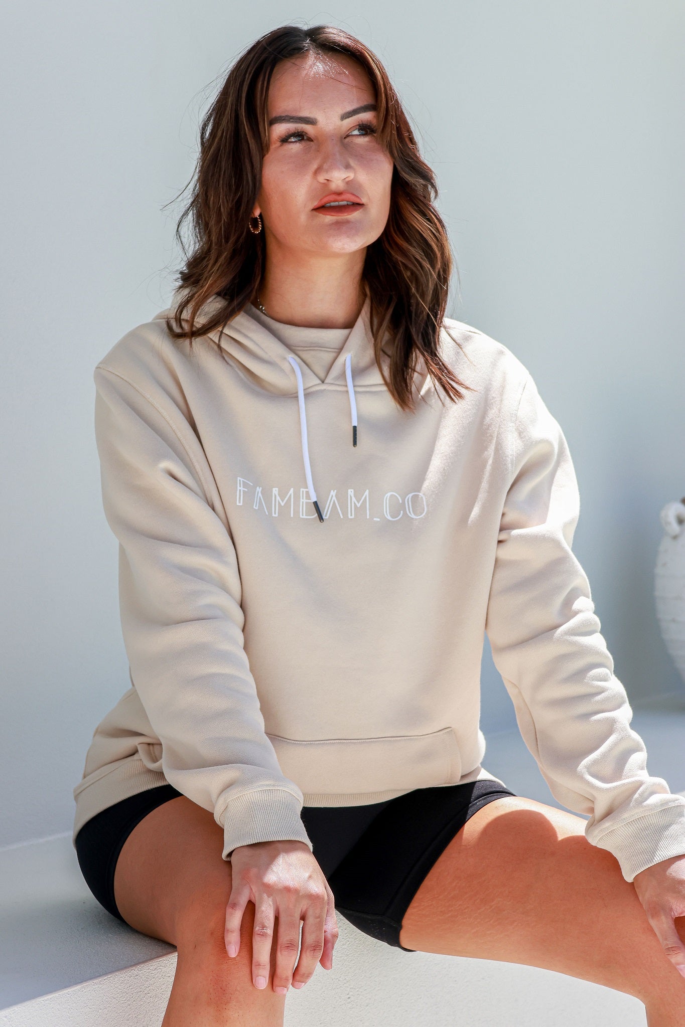 lady sitting wearing beige hoodie jumper logo