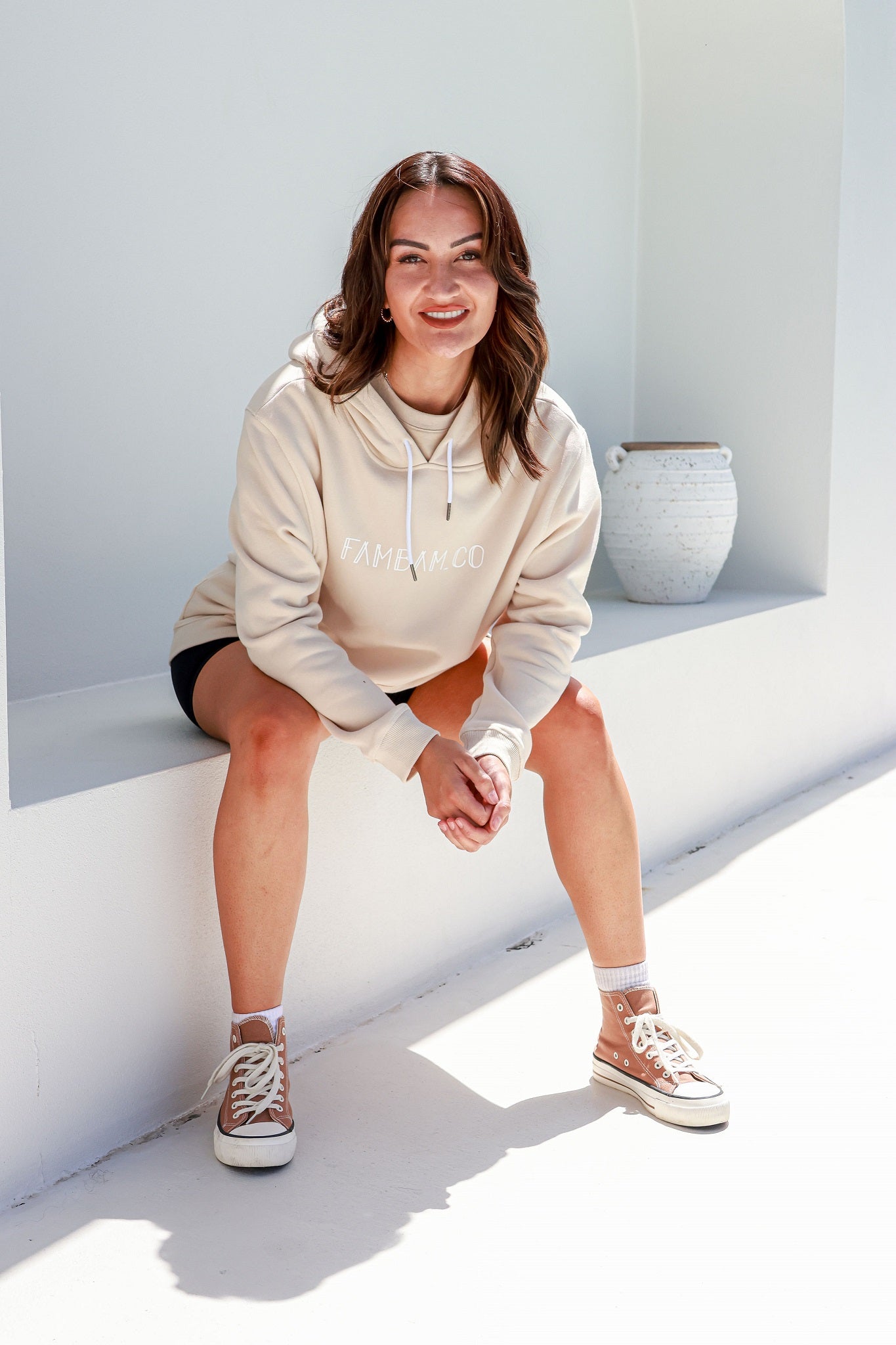 lady sitting in logo beige hoodie smiling