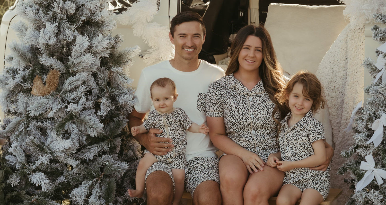 Family sitting together in festive Christmas matching outfits with leopard print patterns, celebrating the holiday season in style.