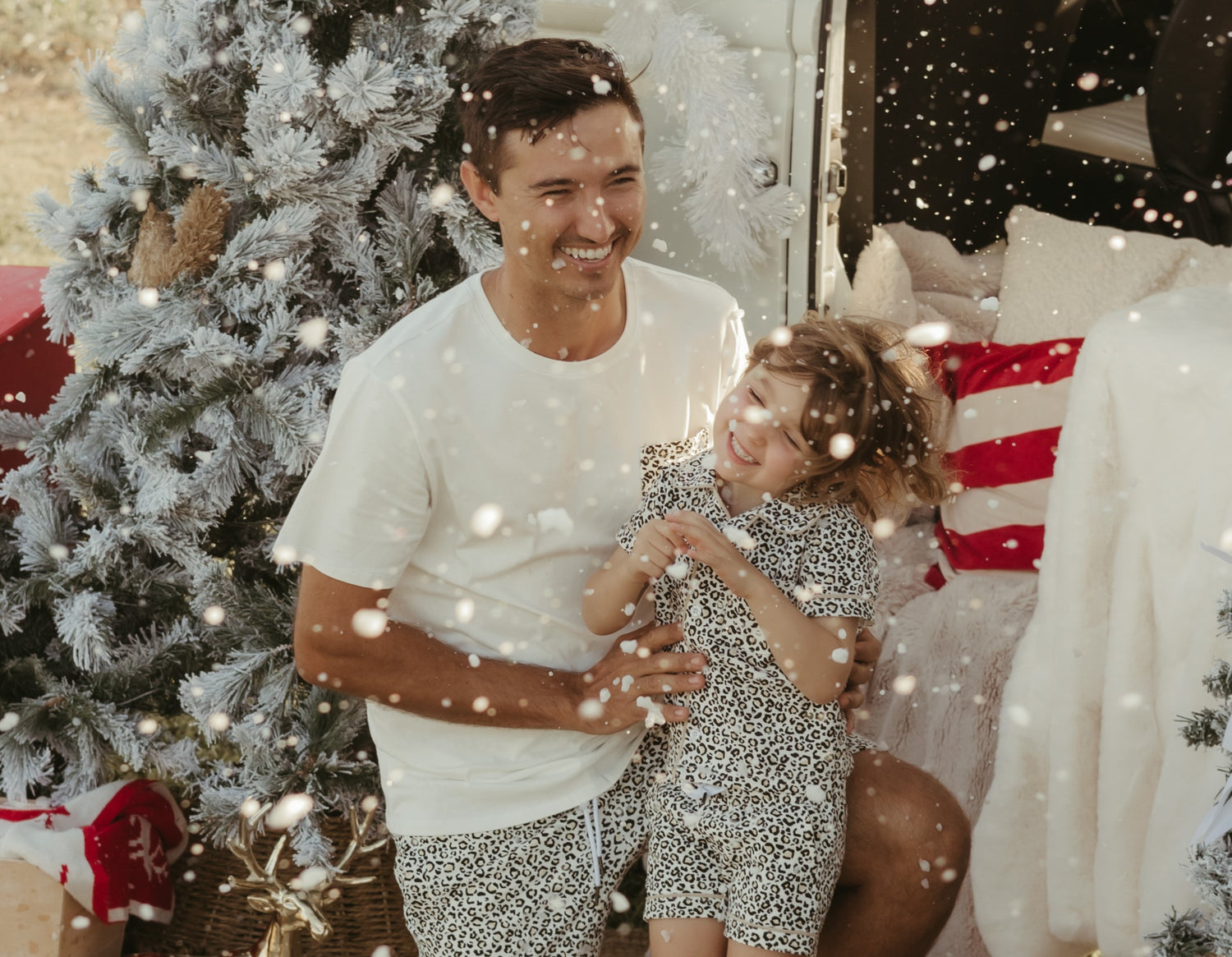 Father and daughter smiling in the snow wearing matching Christmas pajamas — festive family moment perfect for holiday memories