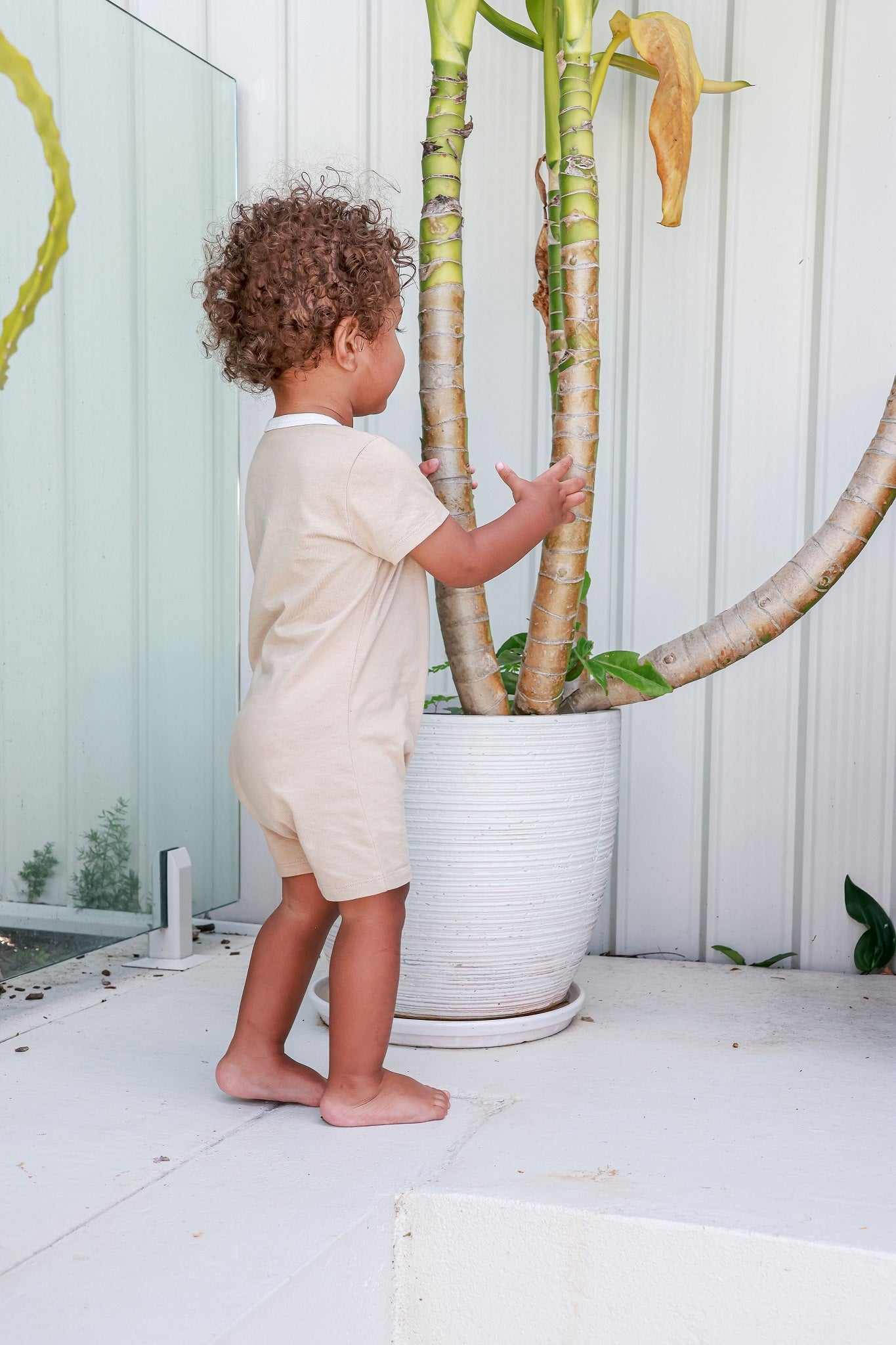 Toddler boy wearing logo beige romper standing