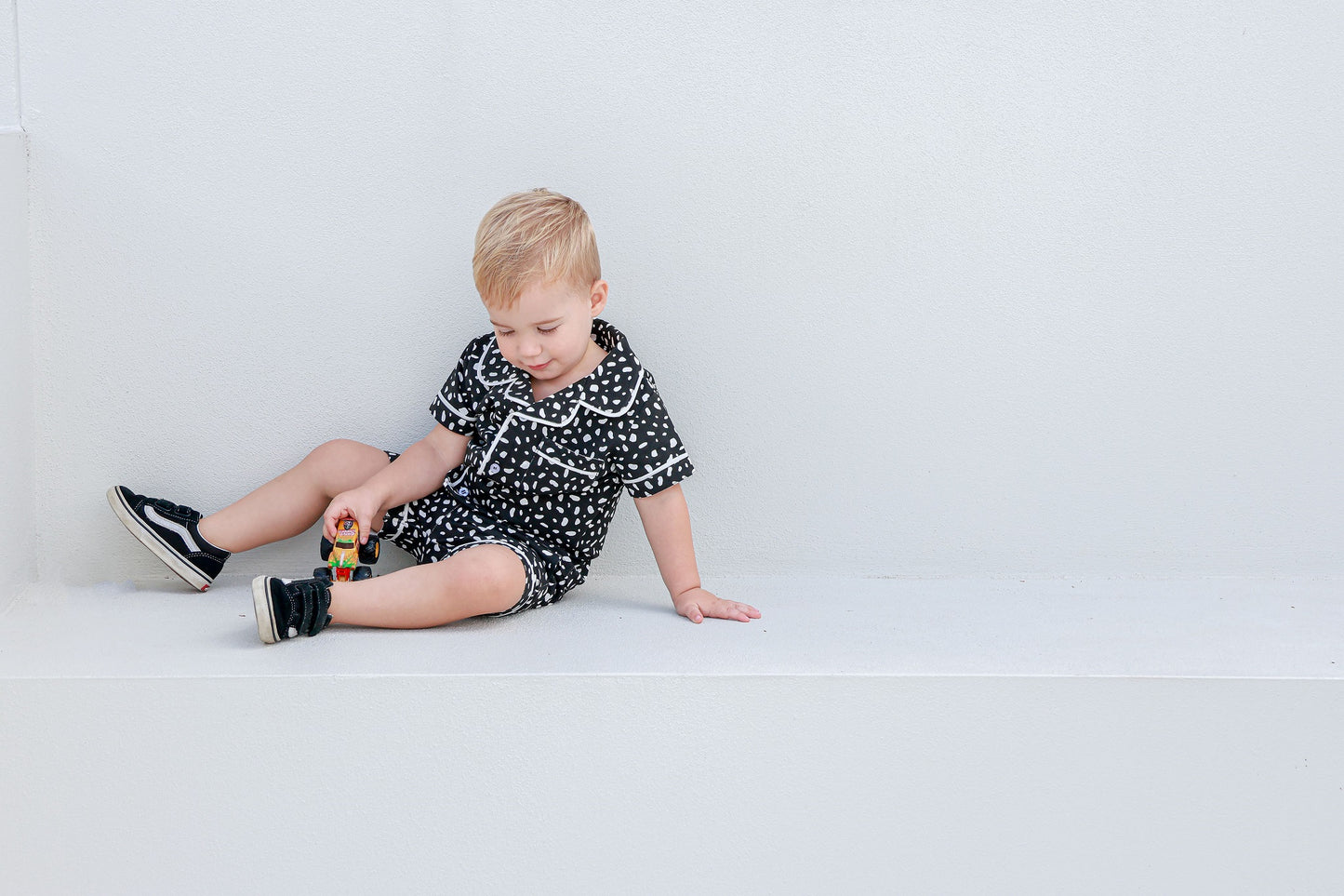 boy sitting down playing with toy truck wearing pyjama set