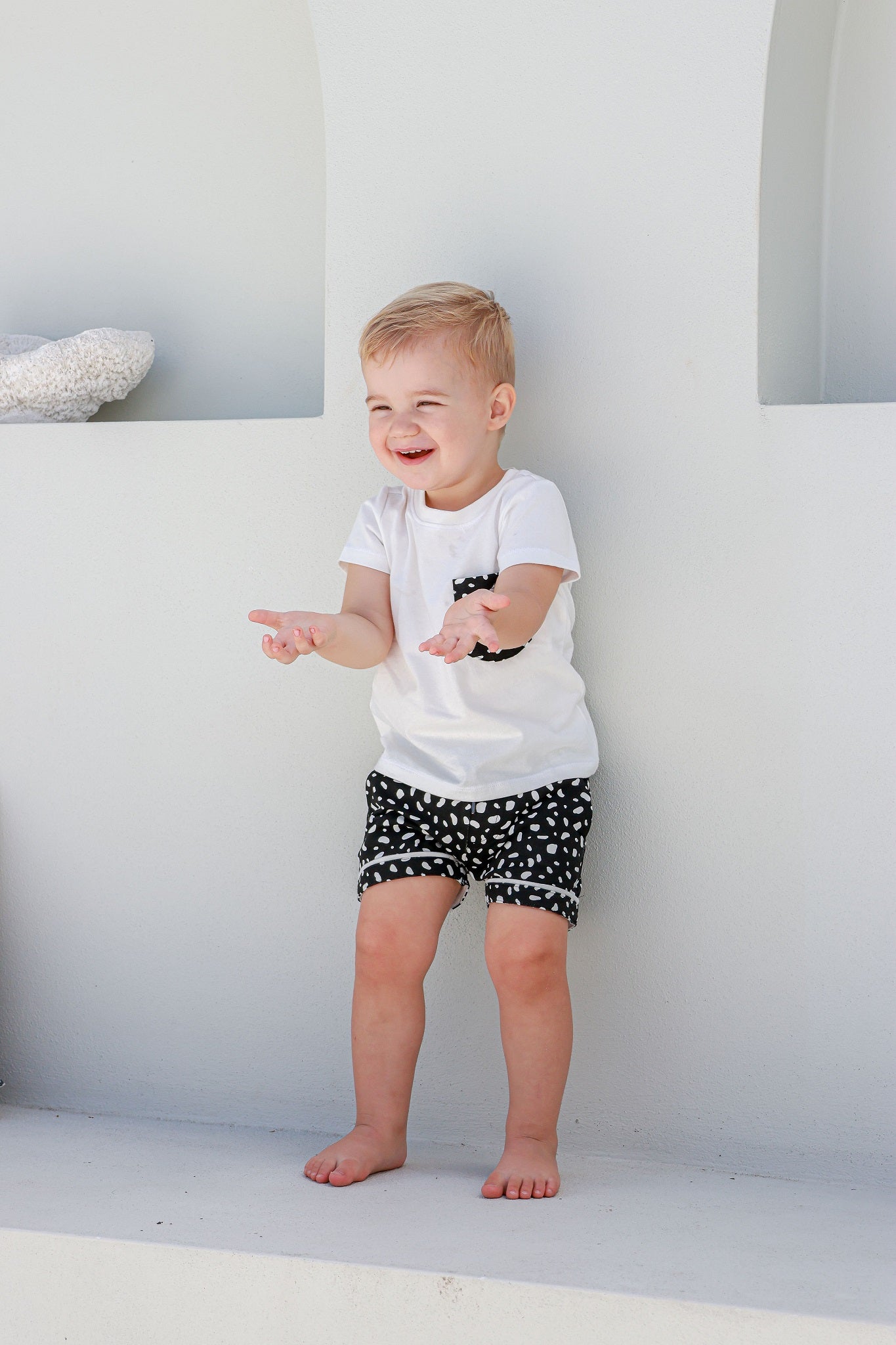 boy standing wearing white and black spotted pyjamas