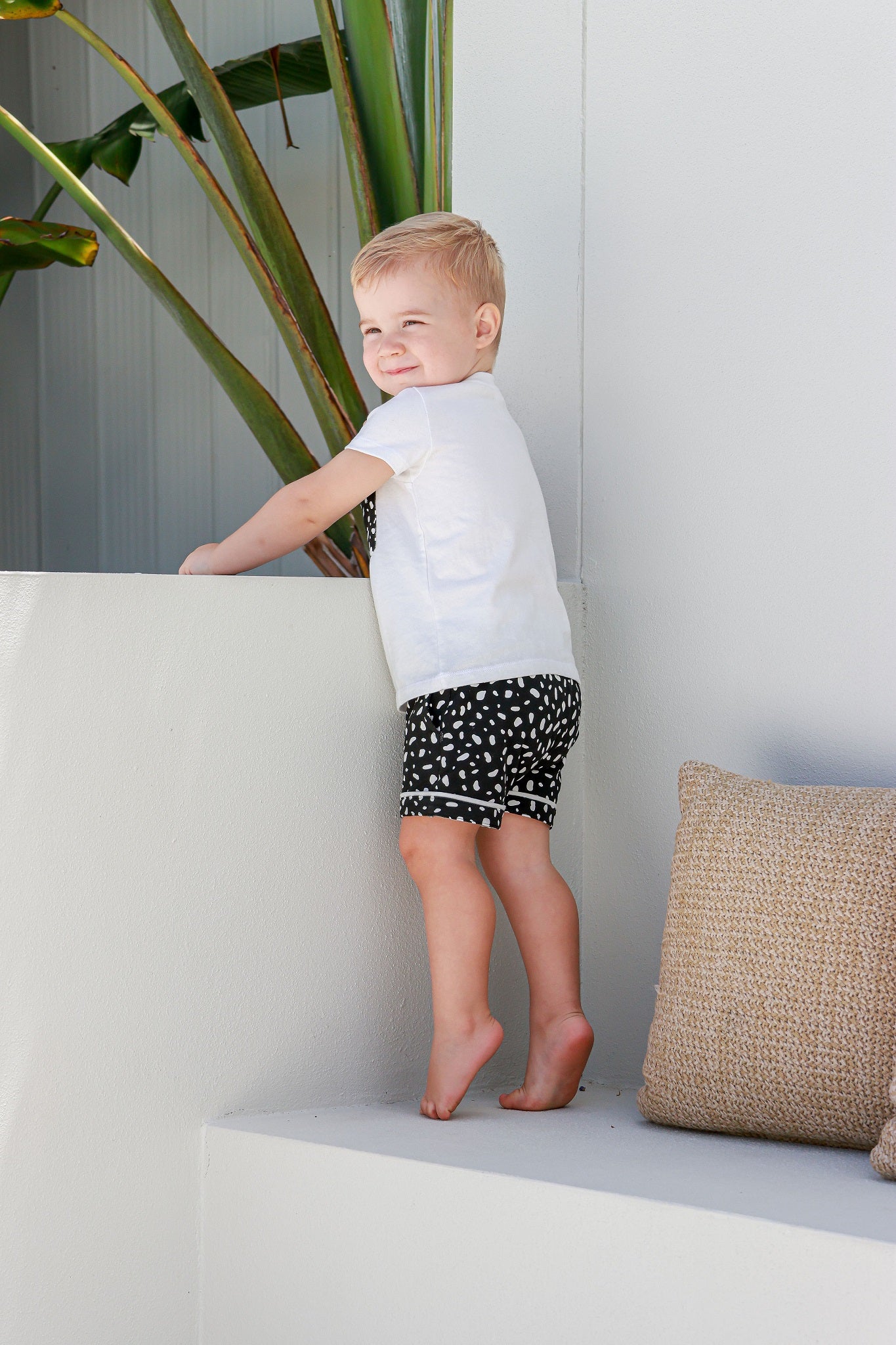 boy standing wearing white and black spotted pyjamas