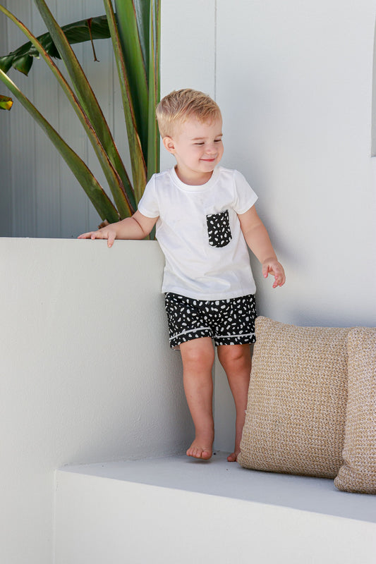 boy standing on white seat in black and white spotted pyjamas