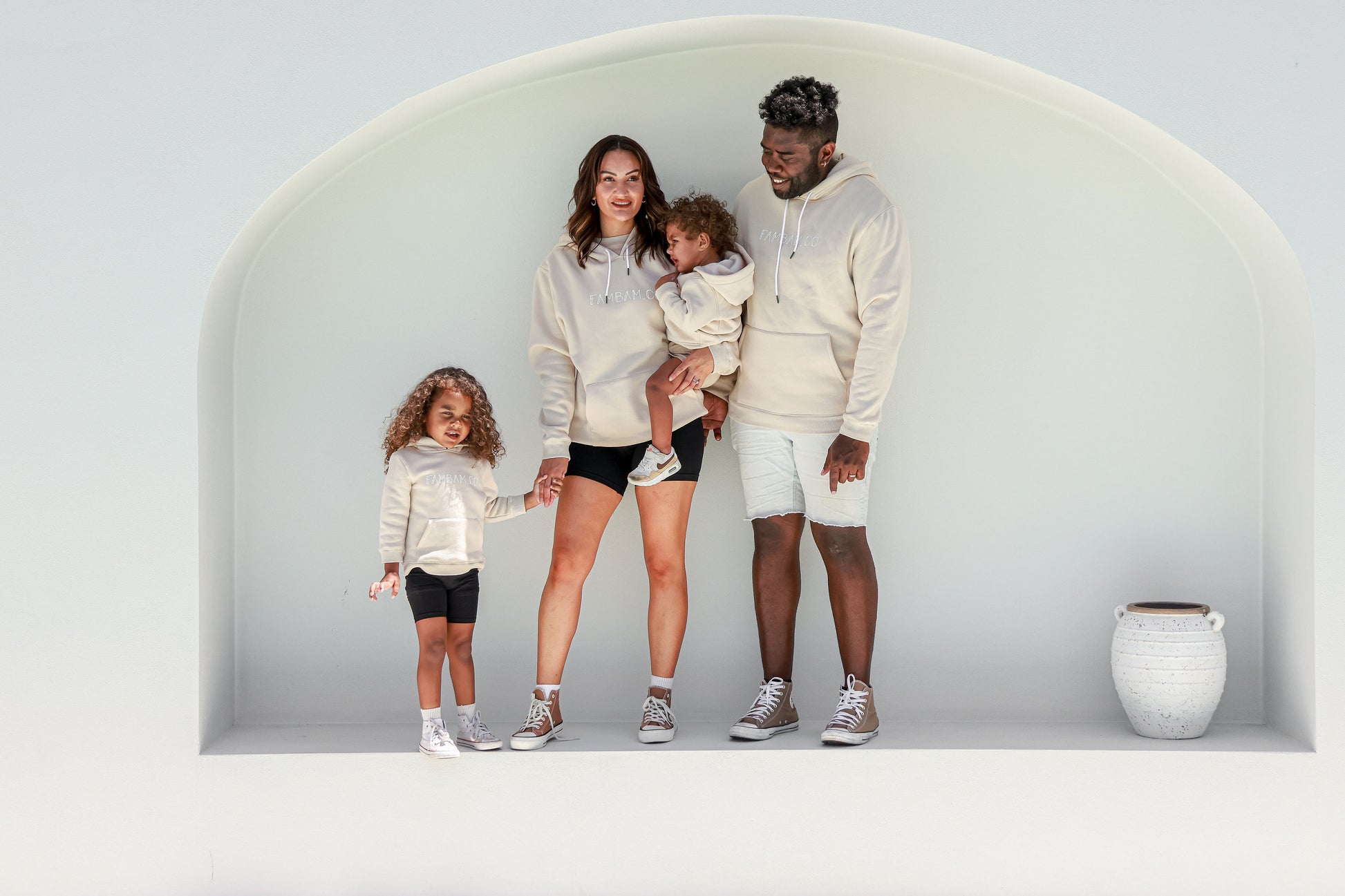 family standing together wearing matching beige hoodies jumpers