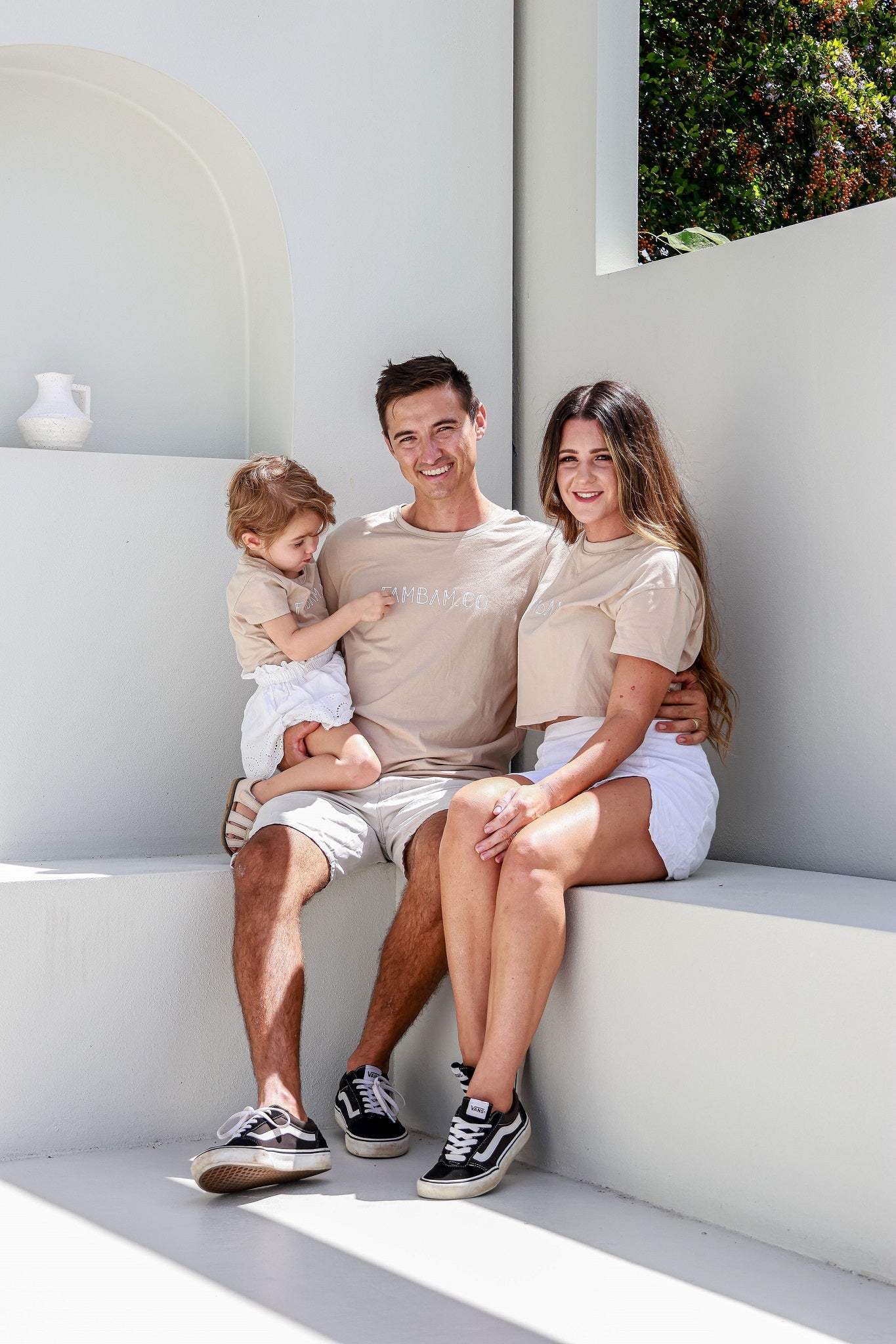 Family sitting together on white bench seat wearing matching shirts