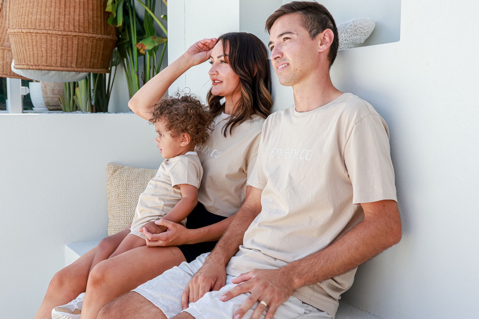 family sitting together wearing matching logo apparel in beige