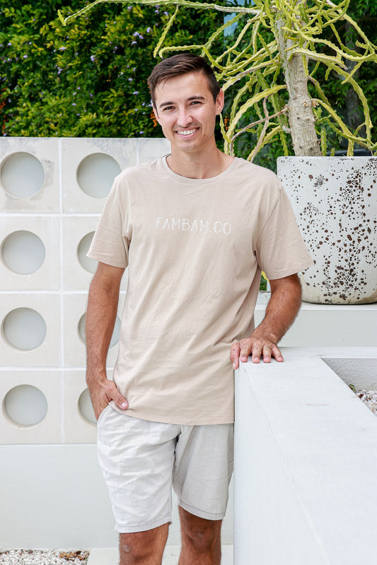 Man standing wearing logo beige shirt smiling