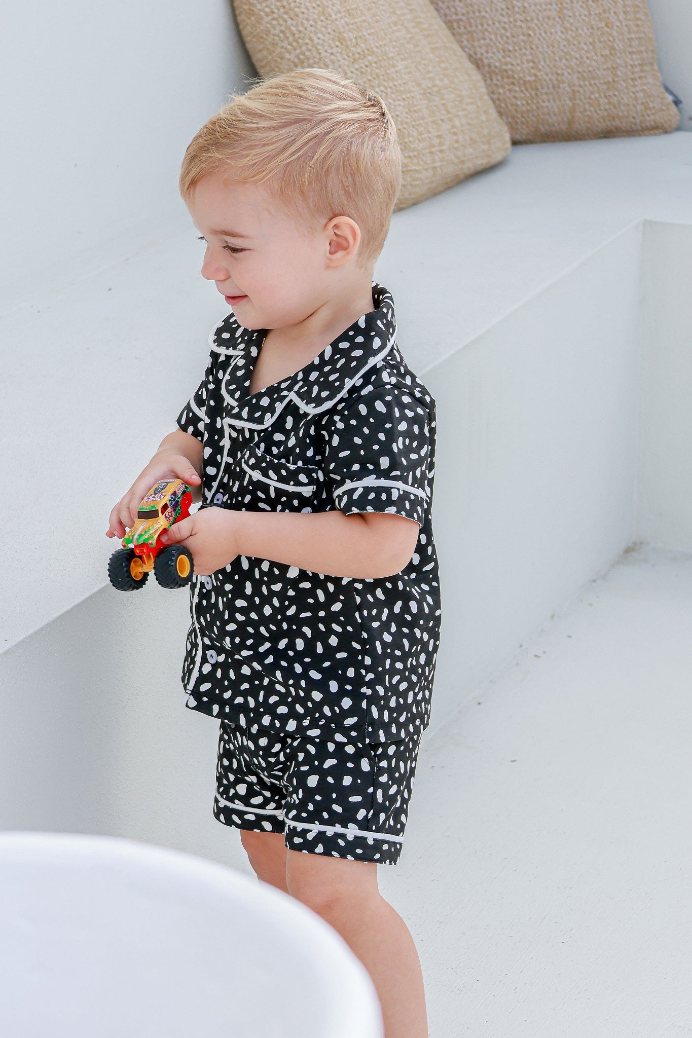 boy standing playing with toy truck wearing pyjama set